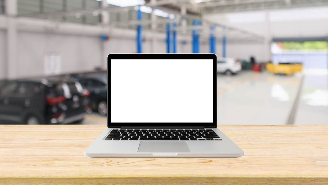 A collision estimator building a documented repair plan on a laptop next to printed OEM procedures and damage photos