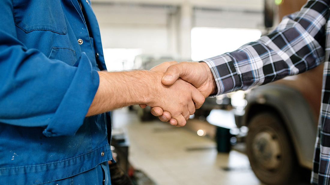 A vehicle owner meeting a certified collision technician inside a clean, modern repair facility