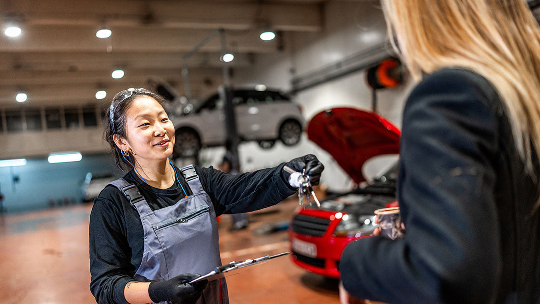 A shop advisor handing loaner car keys to a relieved customer outside a clean collision center