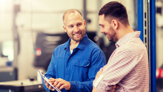 A certified shop estimator reviewing an OEM parts estimate with a vehicle owner at a collision center service desk