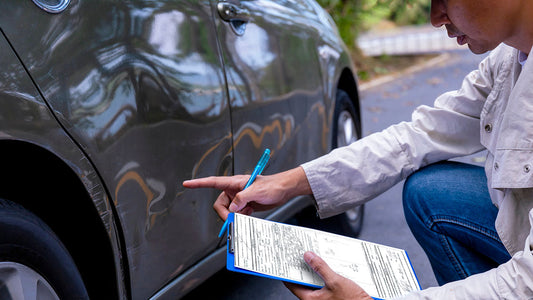 A Lakeside estimator and an insurance adjuster reviewing collision damage on a vehicle together in a repair bay