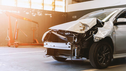 Cutaway of a car front end showing the bumper reinforcement bar, crush cans, and frame rails that absorb crash energy