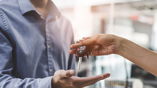 A driver reviewing car rental costs while holding rental keys during an insurance repair