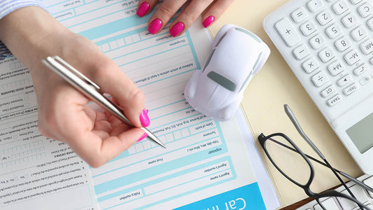 Flat-lay of documents needed to file a car insurance claim including an insurance card, driver's license, a phone with damage photos, and a police report
