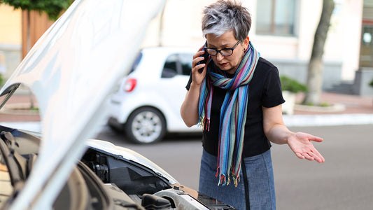 Driver outside a collision repair shop reviewing an insurance policy after learning they have no rental car coverage