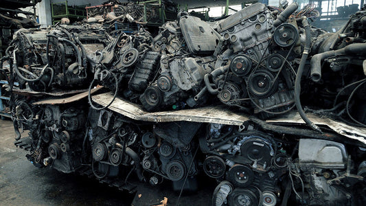 Rows of recycled vehicle body panels in a salvage yard next to a technician inspecting a used door in a clean repair bay