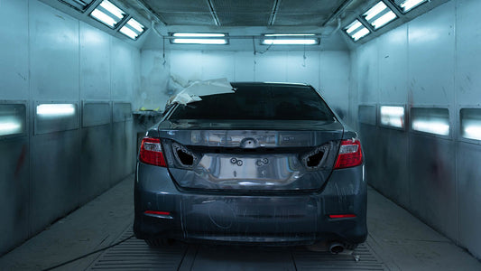 A Rivian R1T electric pickup inside a clean collision repair bay being assessed for damage